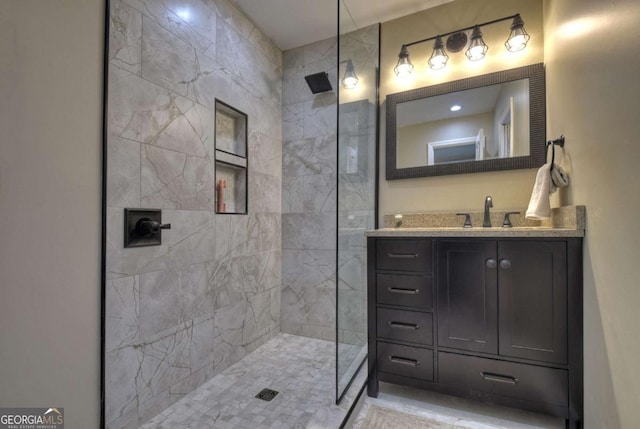 bathroom with tiled shower and vanity