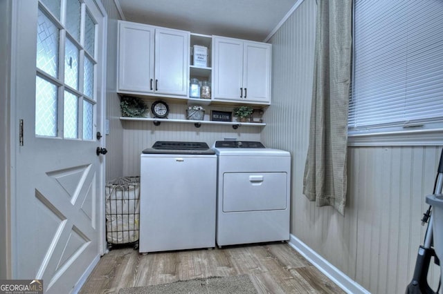 laundry area featuring cabinets, washing machine and dryer, and light hardwood / wood-style flooring