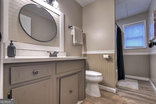 bathroom with vanity, wood walls, a drop ceiling, toilet, and wood-type flooring