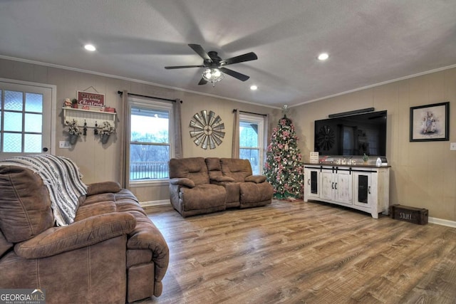 living room with a textured ceiling, ceiling fan, light wood-type flooring, and crown molding