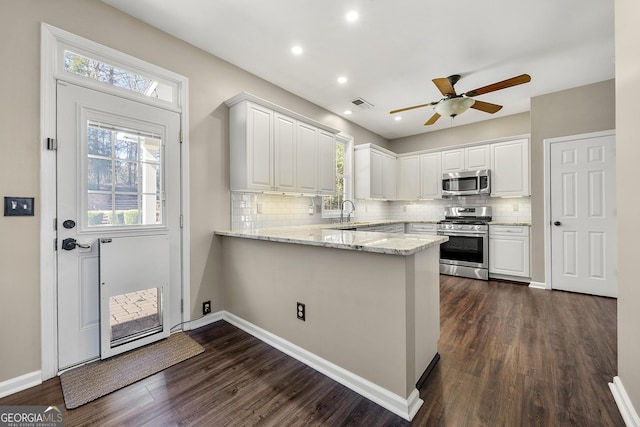 kitchen featuring dark wood finished floors, stainless steel appliances, visible vents, white cabinetry, and a peninsula