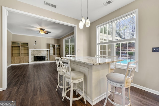 kitchen with hanging light fixtures, dark wood finished floors, a kitchen bar, and visible vents