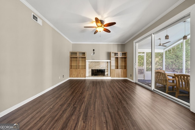 unfurnished living room with baseboards, visible vents, a ceiling fan, a fireplace with raised hearth, and wood finished floors