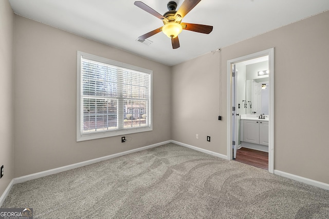 unfurnished bedroom with ensuite bath, baseboards, visible vents, and carpet flooring