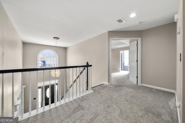 corridor featuring carpet floors, an upstairs landing, visible vents, and baseboards