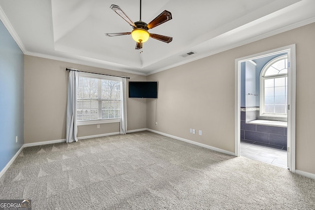 carpeted spare room with baseboards, a tray ceiling, visible vents, and a ceiling fan