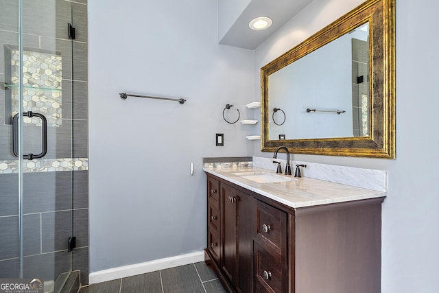 full bath with a tile shower, vanity, and baseboards