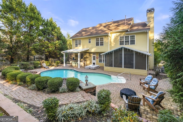 outdoor pool featuring a sunroom and a patio