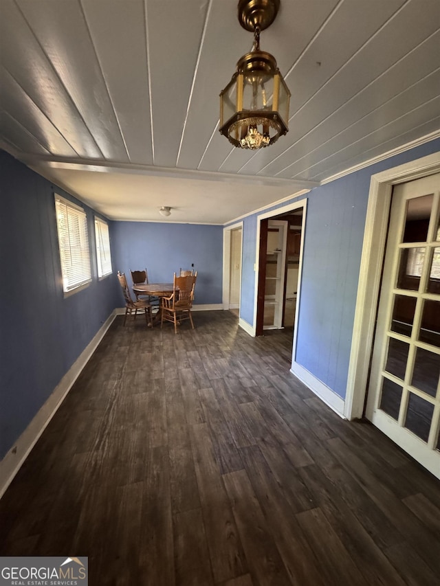 unfurnished dining area featuring crown molding and dark wood-type flooring