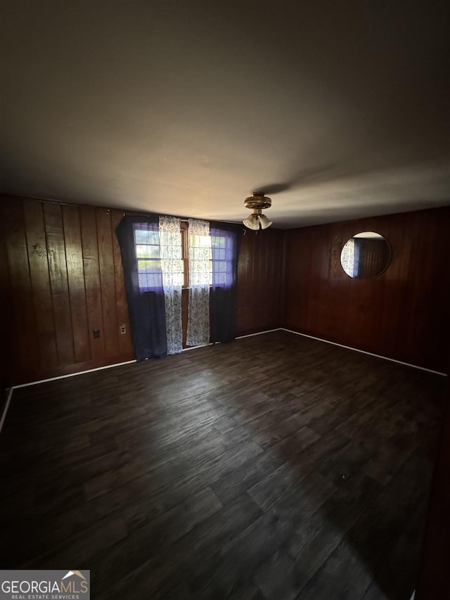 unfurnished room featuring wood walls and dark wood-type flooring