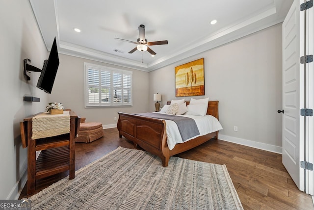 bedroom with visible vents, a raised ceiling, baseboards, and wood finished floors