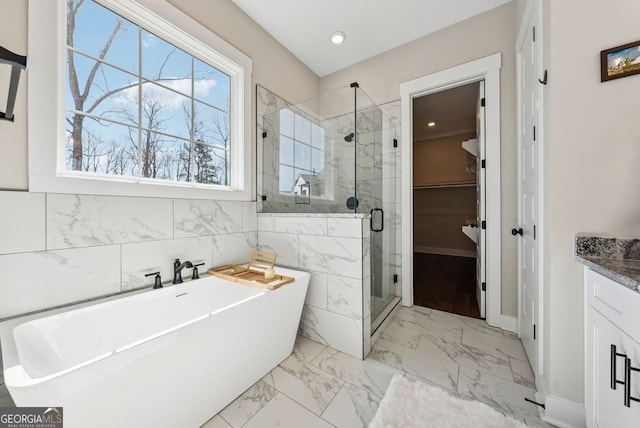 full bath featuring a soaking tub, marble finish floor, a stall shower, and a spacious closet