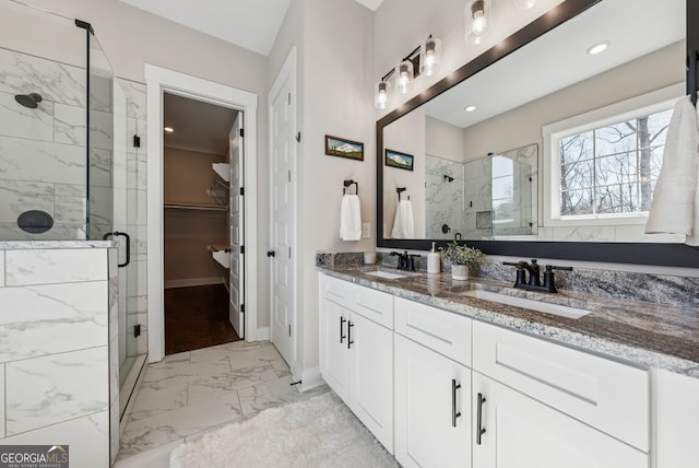 bathroom featuring a walk in closet, a shower stall, marble finish floor, and a sink