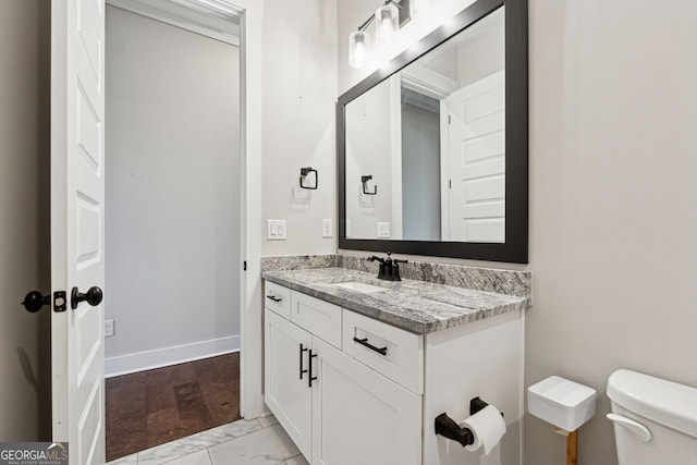 half bathroom featuring vanity, toilet, baseboards, and marble finish floor