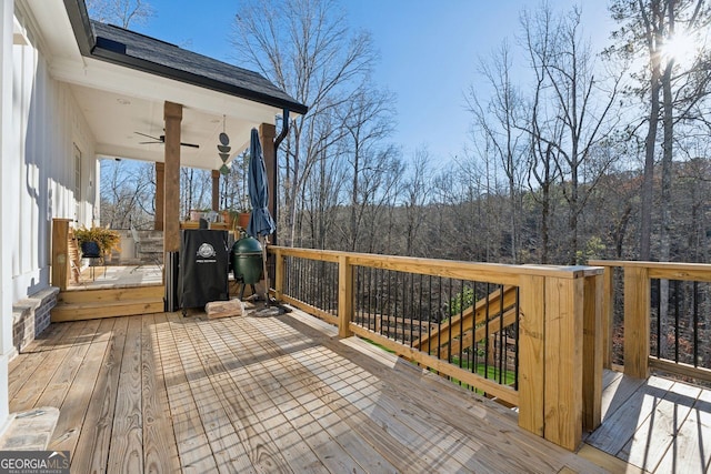 wooden deck with a view of trees and ceiling fan