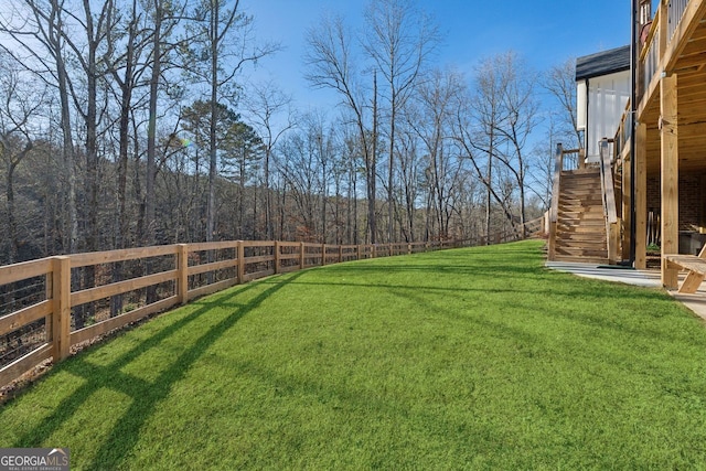 view of yard featuring stairway, a view of trees, and fence