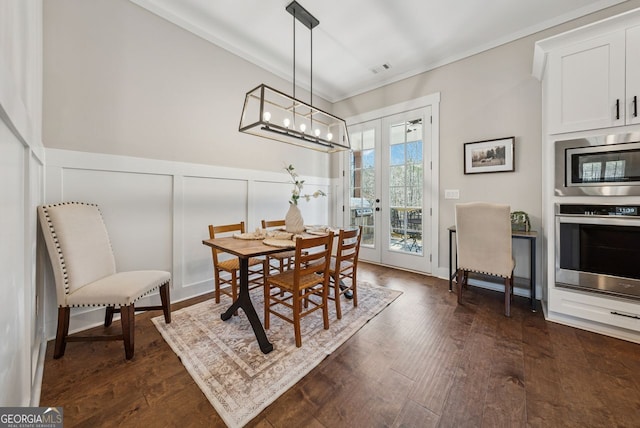 dining space with a decorative wall, french doors, dark wood-type flooring, and ornamental molding