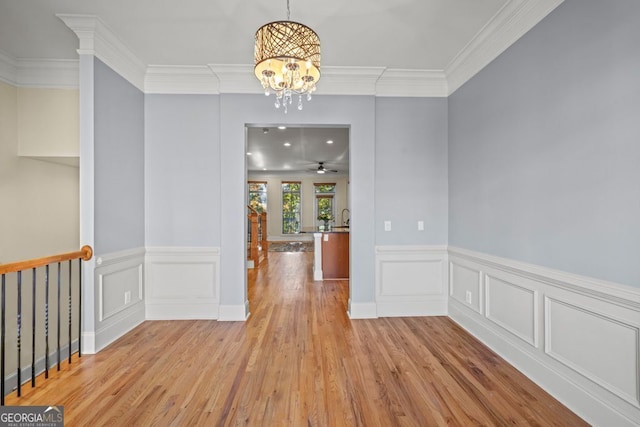 unfurnished dining area featuring crown molding, light hardwood / wood-style floors, and ceiling fan with notable chandelier