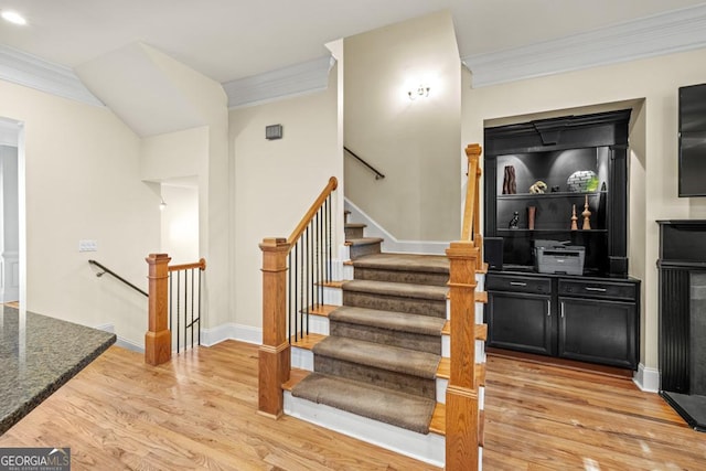 stairs with hardwood / wood-style floors and crown molding