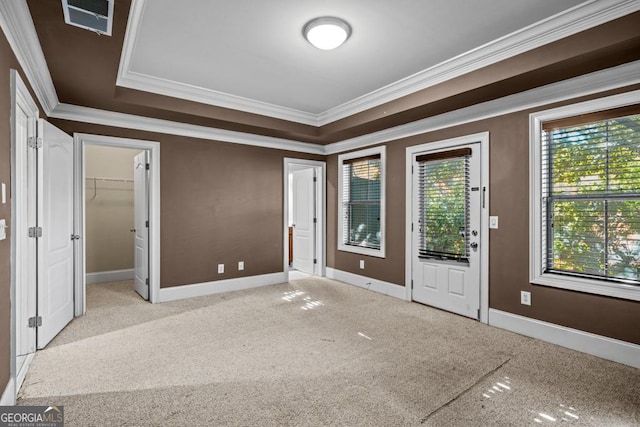 unfurnished bedroom featuring light carpet, a raised ceiling, and crown molding