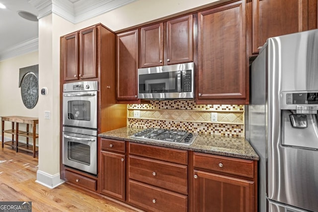 kitchen with dark stone counters, decorative backsplash, ornamental molding, light hardwood / wood-style floors, and stainless steel appliances