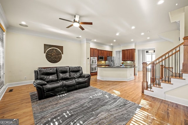 living room featuring ceiling fan, light hardwood / wood-style floors, and crown molding