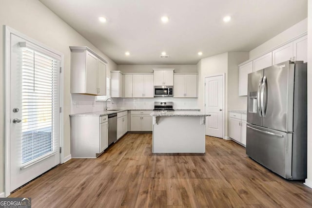 kitchen with white cabinets, stainless steel appliances, a kitchen island, and a wealth of natural light