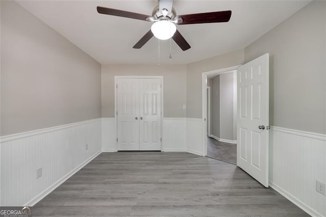 unfurnished bedroom with ceiling fan, a closet, and light wood-type flooring