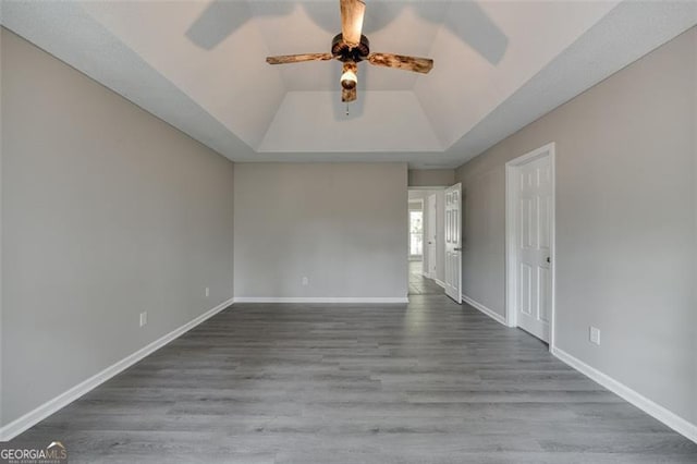 unfurnished room with a tray ceiling, ceiling fan, lofted ceiling, and hardwood / wood-style flooring