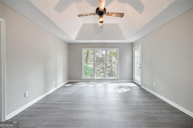 spare room with a tray ceiling, ceiling fan, a textured ceiling, and dark hardwood / wood-style floors