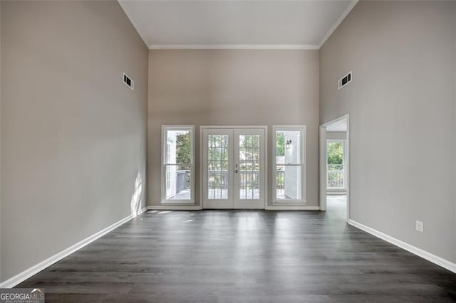 spare room featuring a towering ceiling, dark hardwood / wood-style floors, and ornamental molding