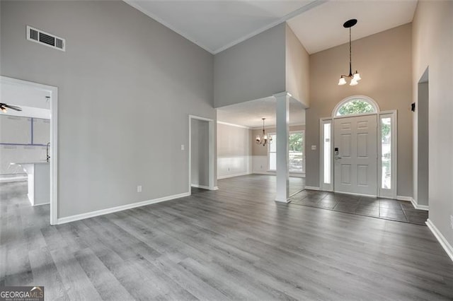 entryway featuring hardwood / wood-style flooring, ceiling fan with notable chandelier, crown molding, and high vaulted ceiling