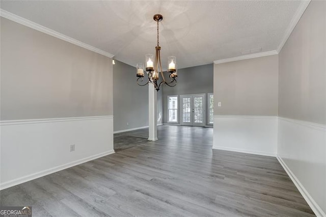 unfurnished dining area featuring a chandelier, french doors, hardwood / wood-style flooring, and ornamental molding