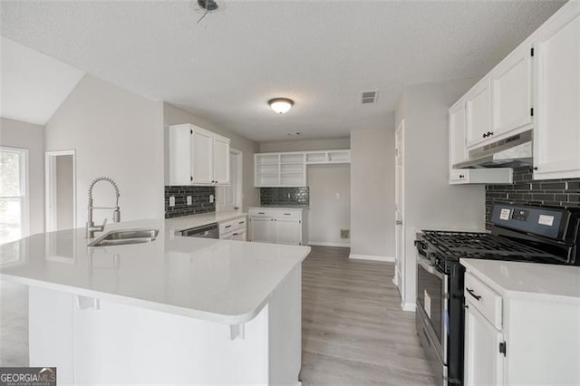 kitchen with white cabinets, sink, gas range, decorative backsplash, and kitchen peninsula