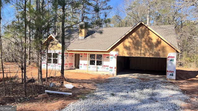 property in mid-construction with a garage, a shingled roof, a chimney, and gravel driveway