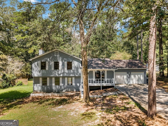 split level home with covered porch, a front yard, and a garage