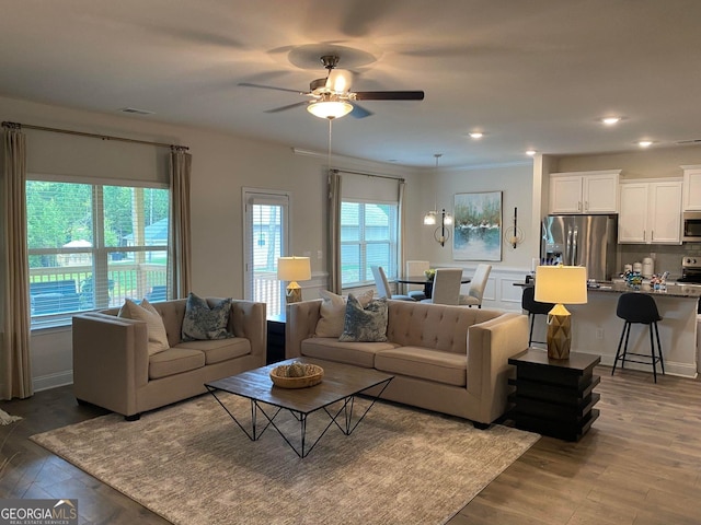 living room with plenty of natural light, ceiling fan, dark hardwood / wood-style flooring, and ornamental molding