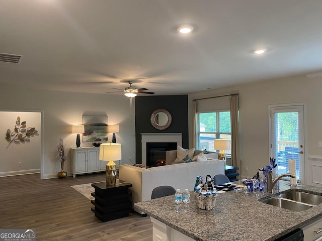 kitchen with a large fireplace, hardwood / wood-style flooring, white cabinetry, and sink