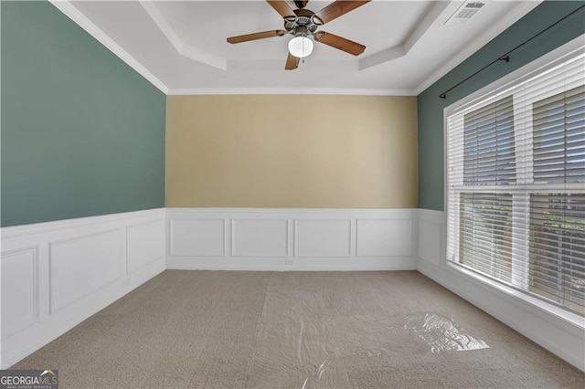 carpeted empty room with ceiling fan, a raised ceiling, and crown molding