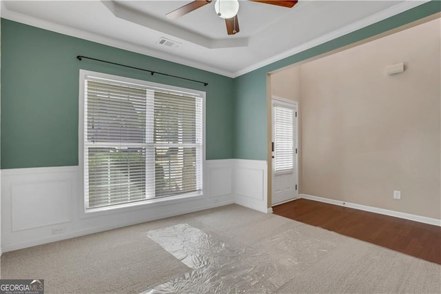 unfurnished room featuring a raised ceiling, ceiling fan, hardwood / wood-style floors, and ornamental molding