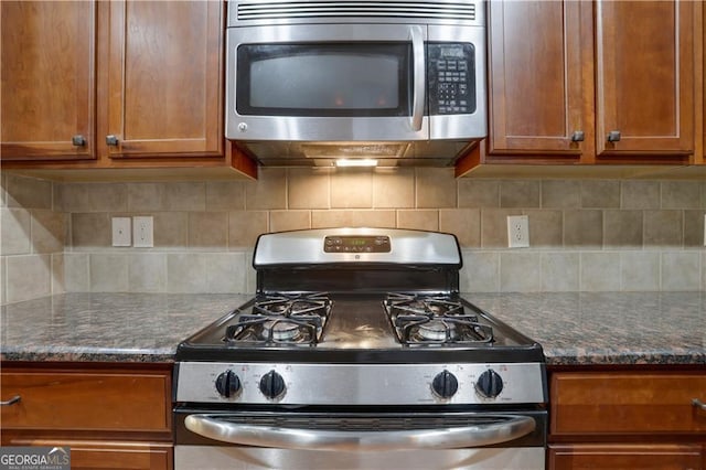 kitchen featuring appliances with stainless steel finishes, backsplash, and dark stone counters