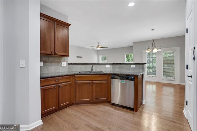 kitchen featuring dishwasher, sink, light hardwood / wood-style flooring, and dark stone countertops