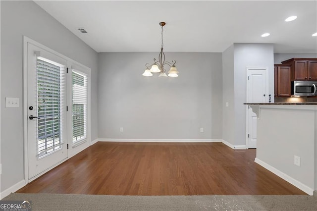 kitchen with pendant lighting, plenty of natural light, dark wood-type flooring, and a chandelier