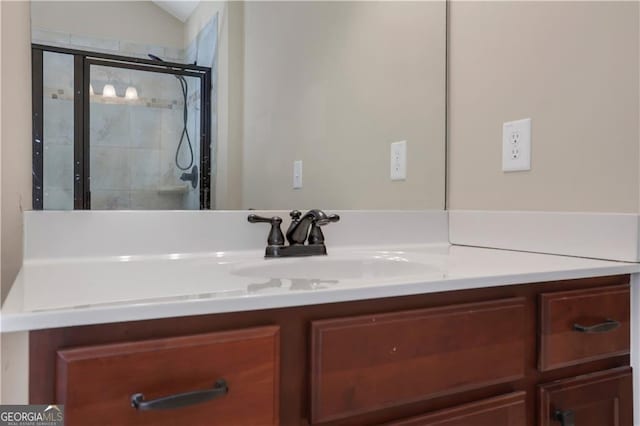 bathroom with vanity, a shower with shower door, and vaulted ceiling