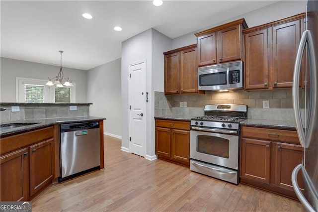 kitchen with an inviting chandelier, hanging light fixtures, sink, light hardwood / wood-style flooring, and appliances with stainless steel finishes