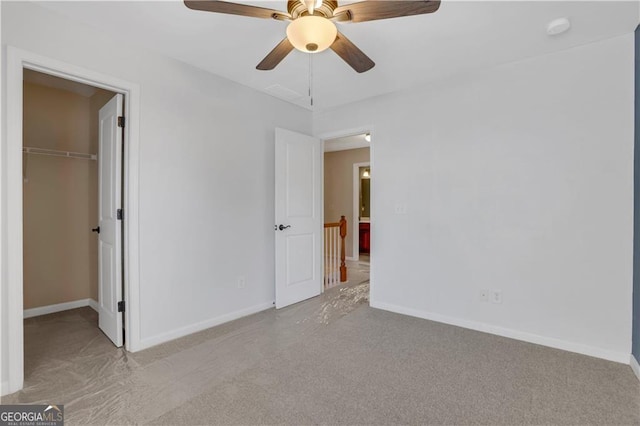 unfurnished bedroom featuring light carpet, a closet, a spacious closet, and ceiling fan