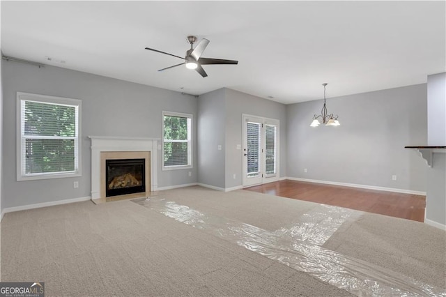 unfurnished living room featuring ceiling fan with notable chandelier and light hardwood / wood-style flooring