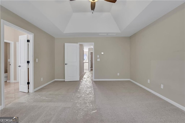 spare room with light carpet, a tray ceiling, and ceiling fan