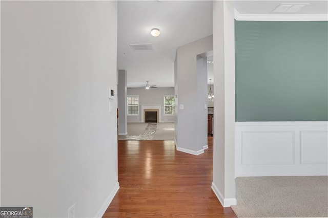 corridor with wood-type flooring and ornamental molding