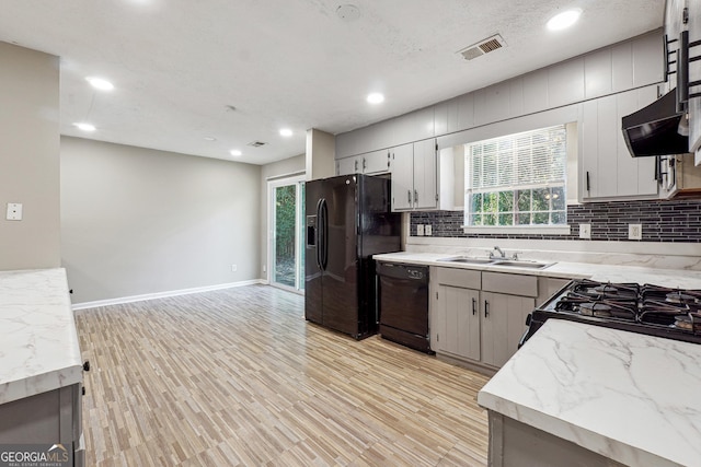 kitchen featuring black appliances, light hardwood / wood-style floors, sink, and a wealth of natural light